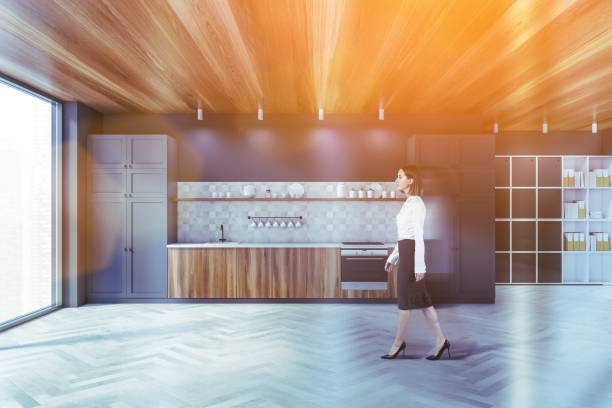 istock Woman walking in gray kitchen with cupboards 1300824526
