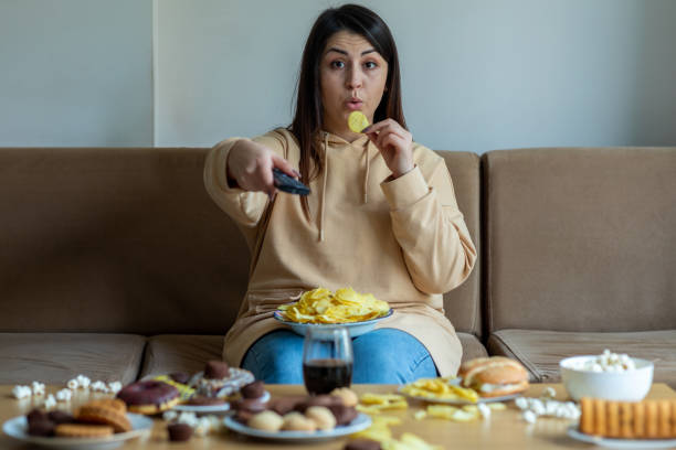 donna sovrappeso sedersi sul divano con cibo spazzatura - brutta abitudine foto e immagini stock