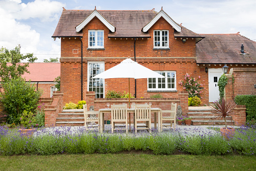Large luxury detached house and garden in UK with garden furniture on a patio in summer
