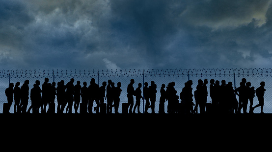 Refugees and immigrants looking for a new life. Column of migrants near the state borders. Fence and barbed wire. Surveillance, supervised. Abandon their lands for a better future. 3d render. Silhouette