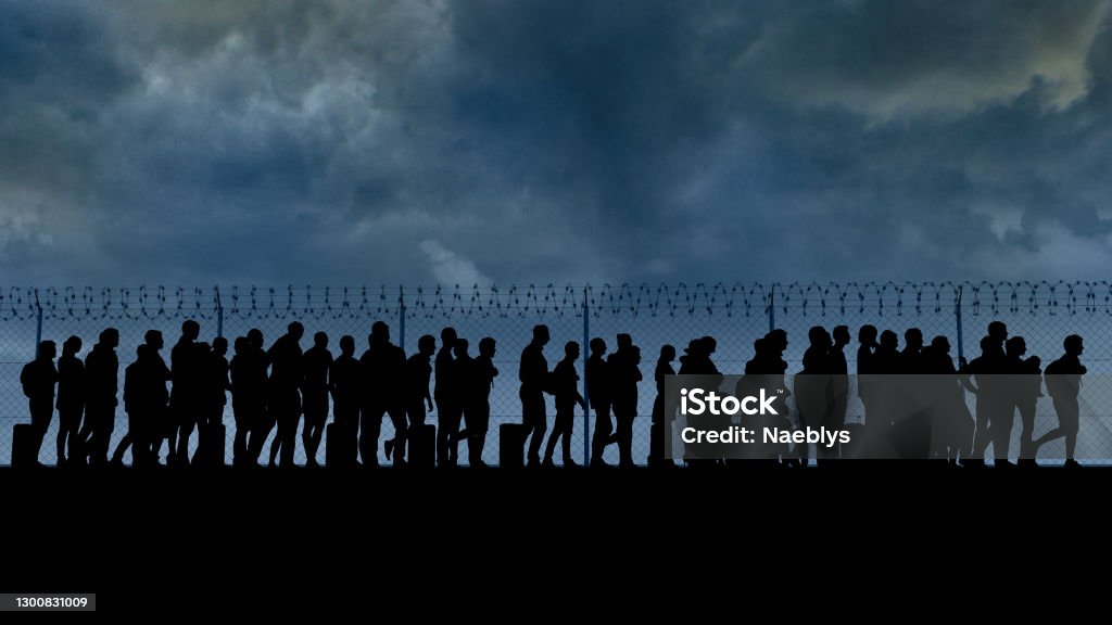 Column of migrants near the state borders. Fence and barbed wire. Surveillance, supervised. Refugees and immigrants Refugees and immigrants looking for a new life. Column of migrants near the state borders. Fence and barbed wire. Surveillance, supervised. Abandon their lands for a better future. 3d render. Silhouette Refugee Stock Photo