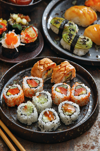 Sushi and sushi roll set (Sake nigiri sushi, notate nigiri sushi, avocado nigiri sushi, Philadelphia rolls, spicy tuna roll, scallop roll). Close-up composition on dark background.