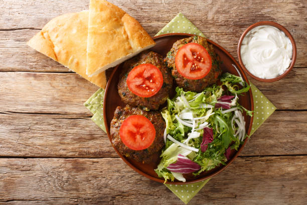 Lamb Patties Chapli Kebab with fresh vegetables close up in the plate. Horizontal top view Lamb Patties Chapli Kebab with fresh vegetables close up in the plate on the table. Horizontal top view from above fresh cilantro stock pictures, royalty-free photos & images