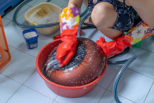 Human hands with gloves washing the pan in the bath pail.