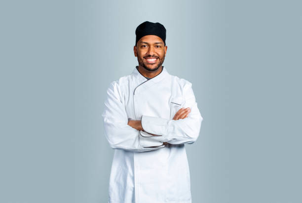 cuoco maschio sorridente su sfondo grigio - chefs whites foto e immagini stock