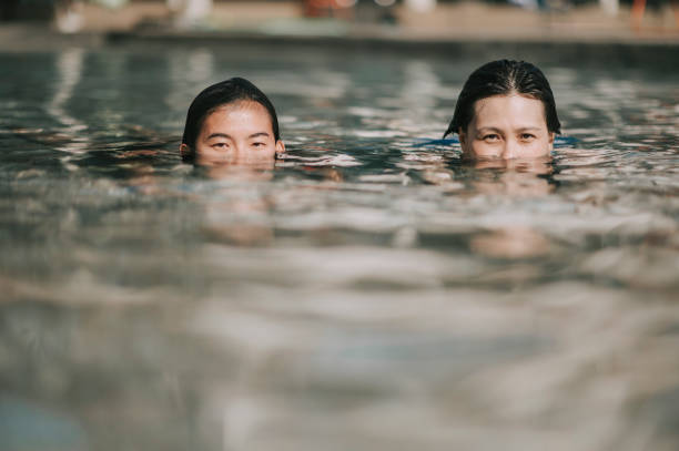 l'allenatore asiatico cinese incoraggia e insegna alla sua studentessa adulta a fare esercizio di respirazione in piscina - women courage water floating on water foto e immagini stock