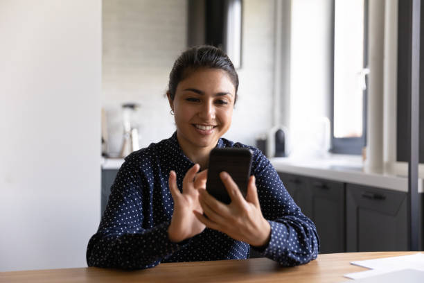 istock Smiling Indian woman using modern smartphone gadget 1300836744