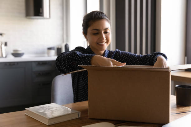 istock Smiling Indian woman unpack box with internet order 1300836765