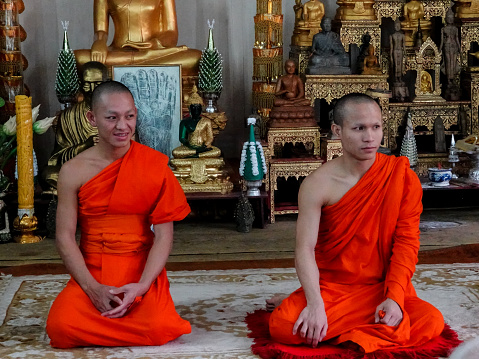 Vientiane, Vientiane, Laos- September 1, 2018: Two young orange robed Buddhist monks sitting in a small temple in Vientiane, Laos.