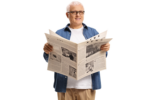 Casual mature man standing and reading a newspaper isolated on white background