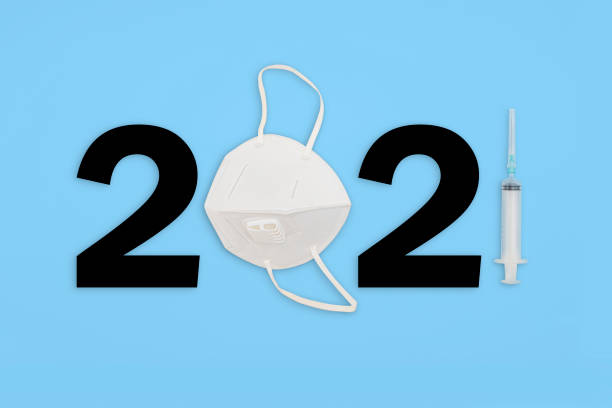 istock Message 2021 with a face mask and a syringe on a blue paper background 1300839863