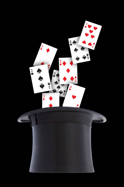 istock Playing cards spill out and scattered from a black top hat upside down on black background. 1300841089