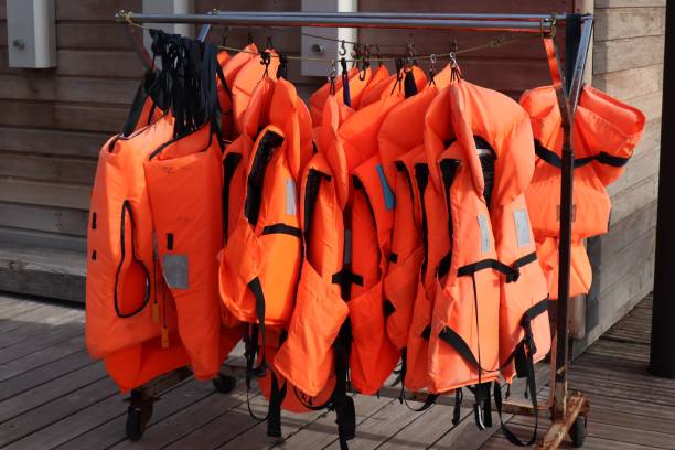 istock Bright orange life jackets hanging on rail 1300841436