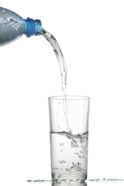 istock Water flows in a glass from a plastic bottle. isolated on white 1300843912