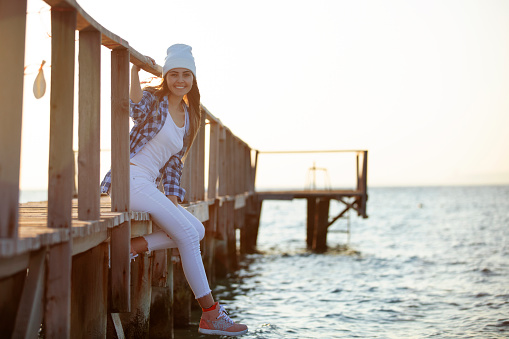 young woman sitting on the pier at sunset