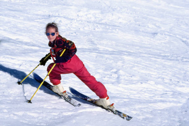 A young skier in colorful gear glides through snow under a sunny sky, showcasing the joy of winter sports and the freedom that people of all ages can experience, Montgenevre ski village, Alps, France