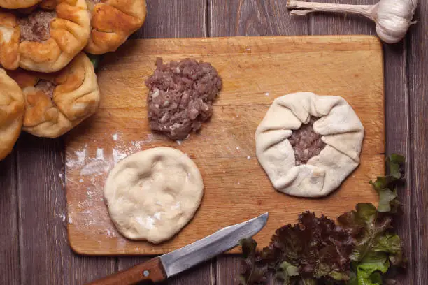 Photo of homemade open meat pies, belyashi. on wooden background.