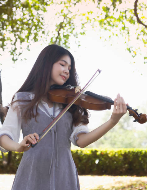 istock Young beautiful lady playing violin with happy feeling,in a park 1300847090
