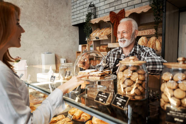 istock Senior baker man in bakery shop serving young woman 1300849749