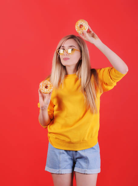 istock Smiling woman in sweater with donuts posing on background. 1300850078
