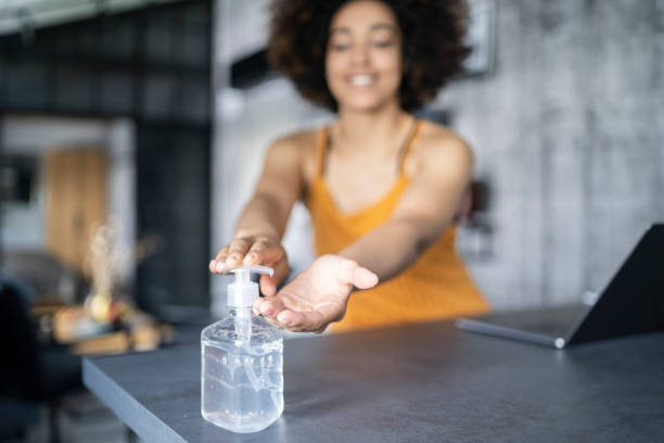 istock Afro American woman disinfecting her hands while working in office 1300850626