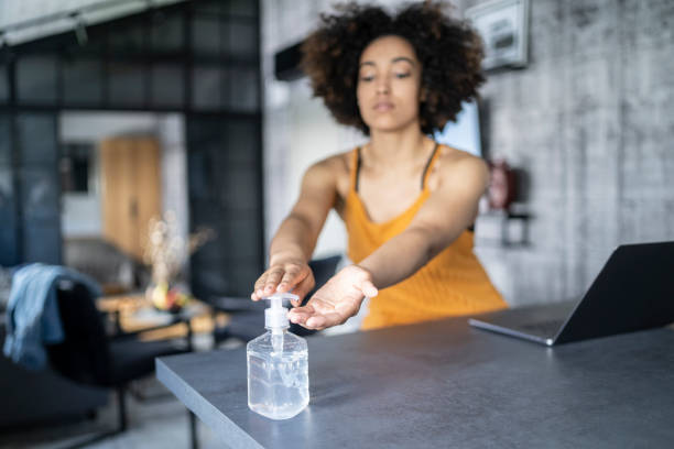 istock Afro American woman disinfecting her hands while working in office 1300850629