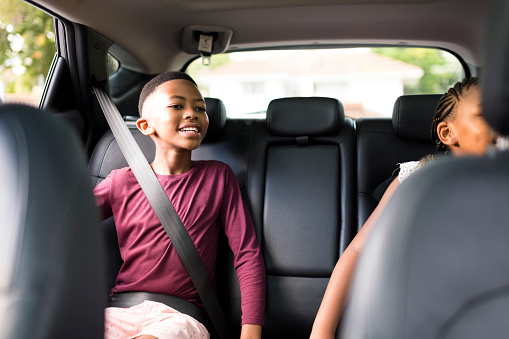 Cape Town, South Africa, Happy boy and sister in backseat of car seatbelts on.