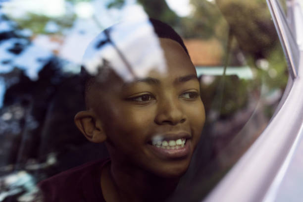Young African boy looking out car window reflections on glass