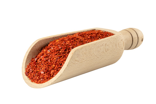 chilli pepper seedless flakes  in wooden scoop isolated on white background. Spices and food ingredients. in Korea known as Gochugaru. Used for Kimchi.