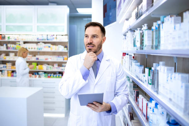 farmacéutico masculino profesional guapo en bata blanca sosteniendo tableta y pensando en farmacia tienda o farmacia. atención médica y boticario. - scientist lab coat doctor male fotografías e imágenes de stock