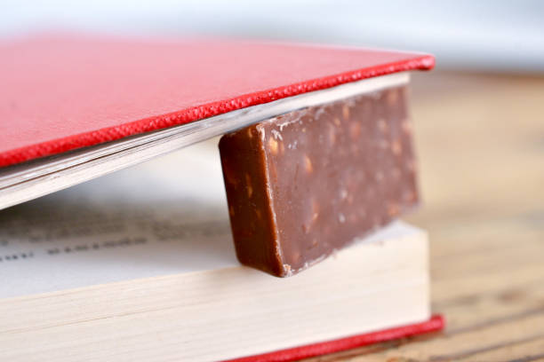 chocolate con frutos secos entre páginas en un viejo libro - chocolate book brown book cover fotografías e imágenes de stock