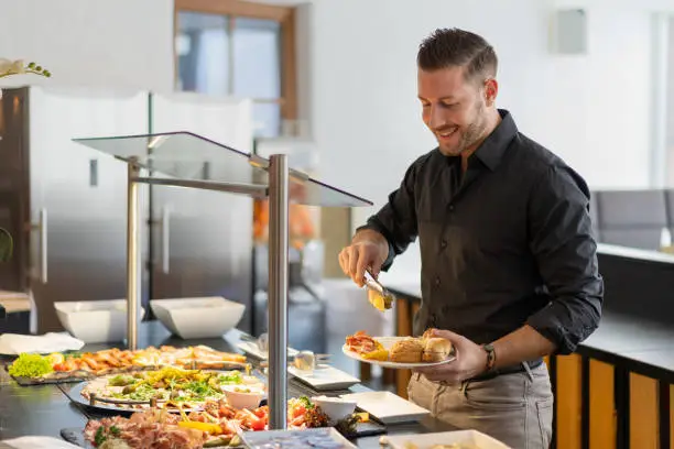 man enjoying stay in hotel taking food from snach buffet in the afternoon