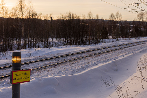 Mellansel, Vasternorrland, Sweden, dangerous unattended railway crossing with a lamp that goes out when a train is comming as stated on the sign.
