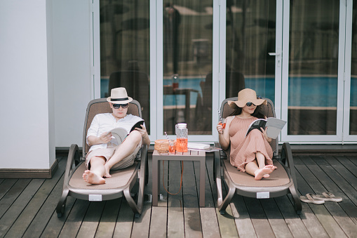 asian chinese couple enjoying leisure time at backyard poolside relaxing with afternoon tea break