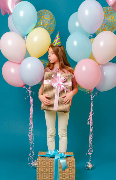 1 ragazza bianca di 10 anni con un regalo, rosa, giallo, palloncini blu per una vacanza su sfondo blu, adolescente, - 10 11 years cheerful happiness fun foto e immagini stock