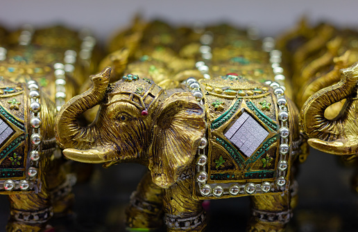 Golden colored elephant figures with trunk up. Souvenir store gift, good luck concepts