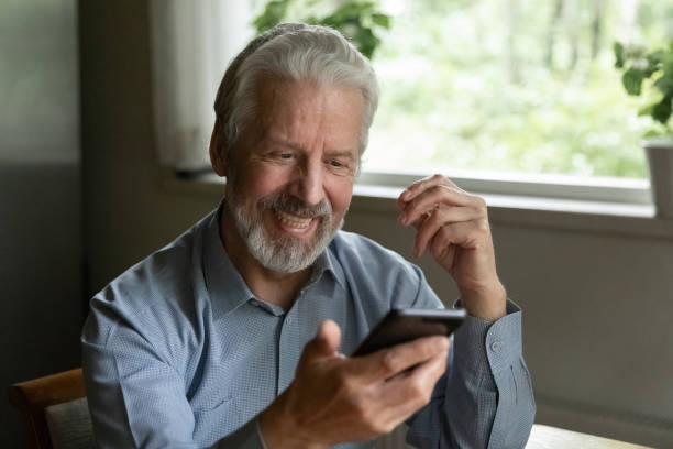 istock Close up smiling happy mature man looking at phone screen 1300870953