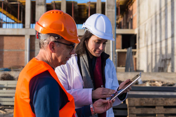 istock Employees with helmets and work clothes use a tablet outside 1300871880
