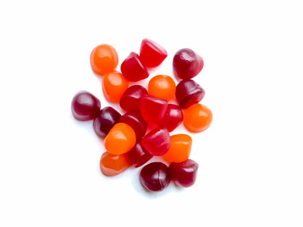 grupo de gomas multivitamínicos vermelhas, laranjas e roxas com a garrafa isolada no fundo branco. conceito de estilo de vida saudável. - gummy - fotografias e filmes do acervo