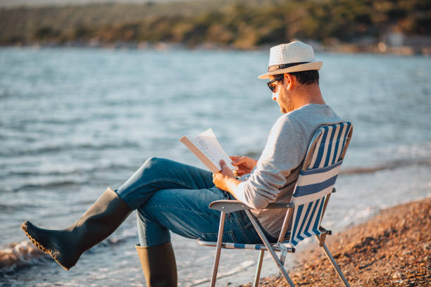 istock Young Man Reading a Book on the Beach 1300876012