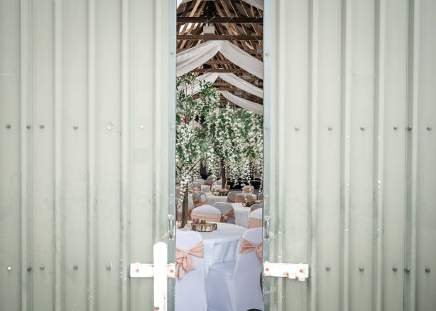 Wedding reception party laid out behind rustic doors in traditional old converted farm barn