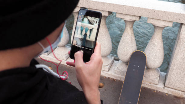 jovem patinador caucasiano, tirando fotos com seu smartphone na cidade de ljubljana. - alenka - fotografias e filmes do acervo