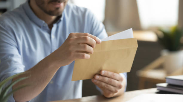istock Close up young man opening envelope with paper correspondence. 1300879253