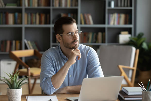 istock Distracted from work pensive young man looking in distance. 1300879262