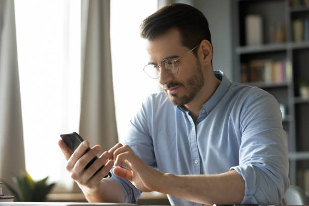 istock Happy smiling millennial man using smartphone applications at home. 1300879268