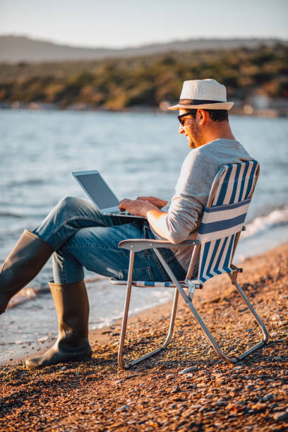 istock Freelance Young Man Working on Laptop on the Beach 1300880509
