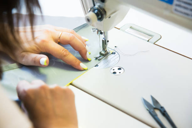 istock Woman hands with fabric at sewing machine 1300882232