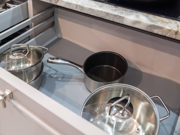 istock Opened drawer with pots and pans inside in beige kitchen with marble countertop 1300882297