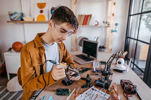 istock Teenage boy soldering elements on circuit board 1300883545