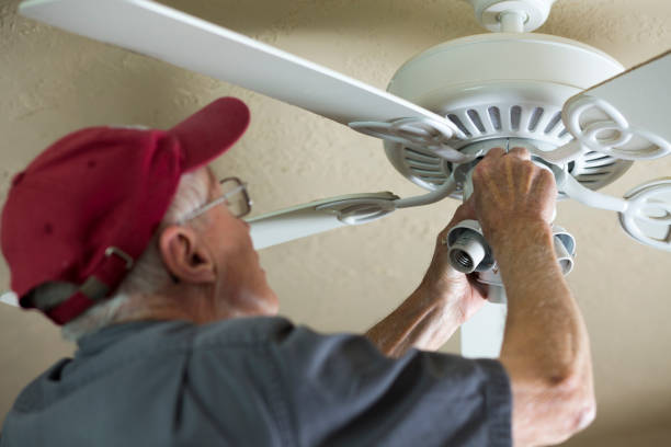 Electrician repairing ceiling fan.  He replaced the motor for the fan.  Blue collar Caucasian senior man still active and enjoying do small repairs for others. Electrician repairing ceiling fan for neighbor.  He replaced the motor for the fan.  Blue collar Caucasian senior man is retired but is still active and enjoying doing small repairs for others.  
Helping neighbors. ceiling fan stock pictures, royalty-free photos & images